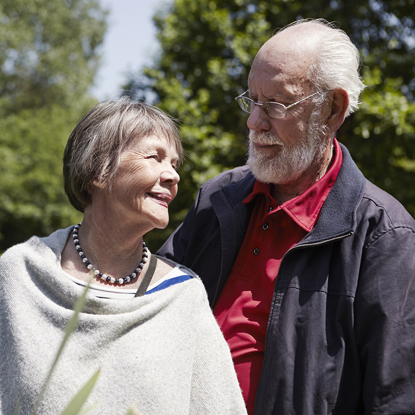 ett äldre par ler och håller om varandra